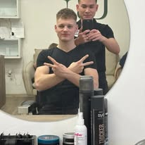 Spokojený klient s hotovým střihem a barber v zrcadle